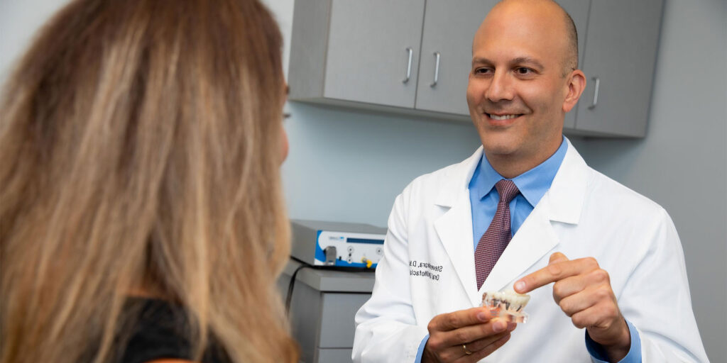 doctor showing patient implant model within the dental practice